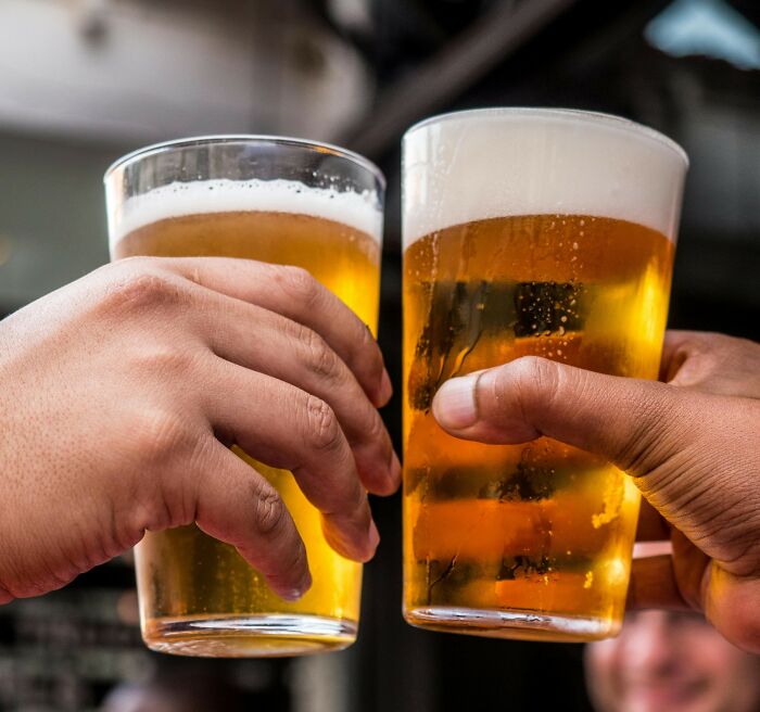 Two people clinking glasses of beer, highlighting a casual moment with drinks.