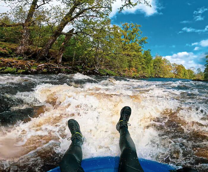 View from a person rafting downstream with rushing water and trees, capturing an adventurous moment with memorable strangers.