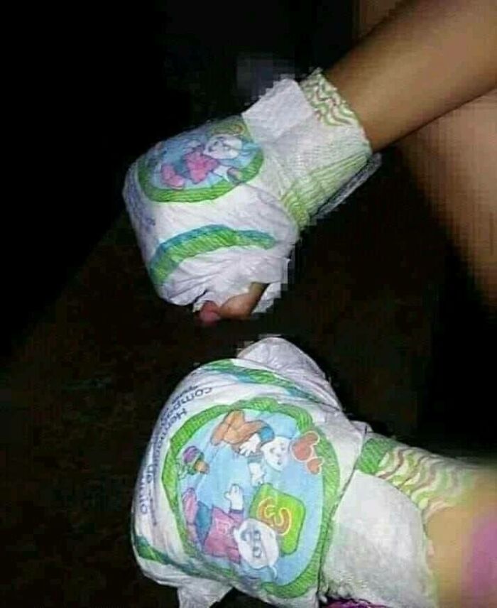 Hands humorously wrapped in baby diapers with cartoon prints.