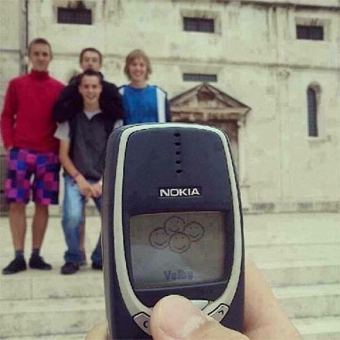 A Nokia phone used to snap a group photo, showing the iconic Snake game screen.