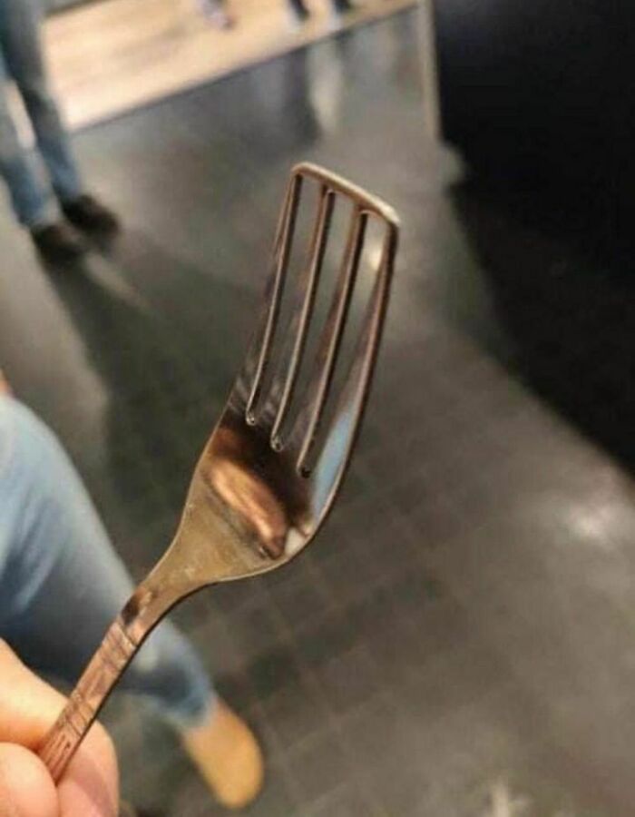 A fork with bent prongs held up in the air, creating a humorous image without needing context.