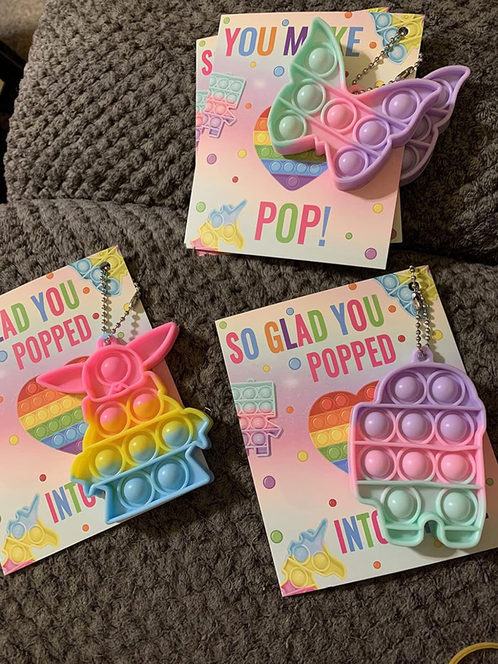 Colorful pop-it toys with Valentine's Day cards for kids on a textured surface.