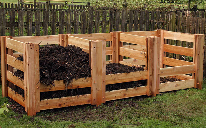Three bin wooden composter bins in a backyard Three bin wooden composter bins in a backyard