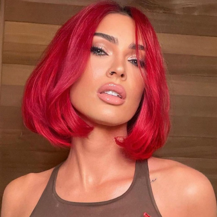 A person with vibrant red hair poses confidently, highlighting fashion trends.