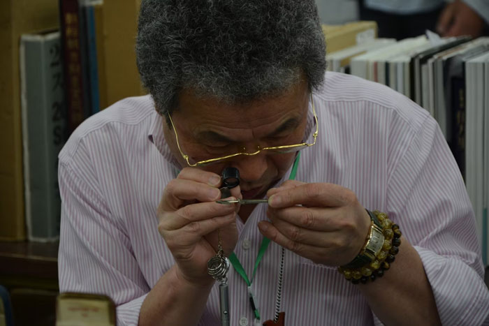 Man closely examining a small object with a magnifier, surrounded by books, illustrating weird fun facts to know.
