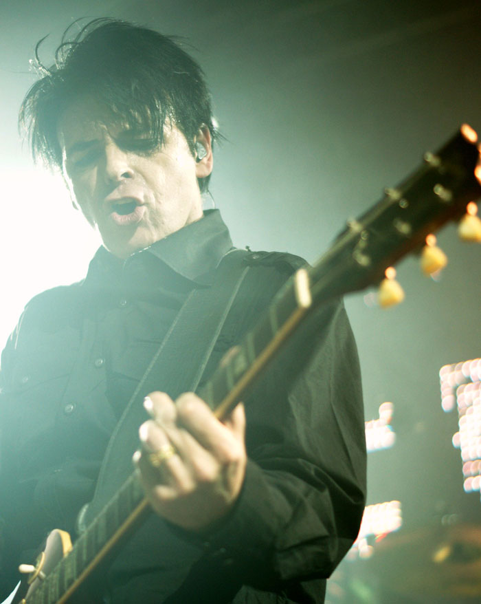 Rock musician playing guitar passionately on stage with bright lights in the background, representing fun facts theme.