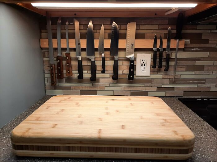 Modern kitchen counter with cutting board, magnetic knife strip, undercabinet light and tiled backsplash, kitchen feel like new