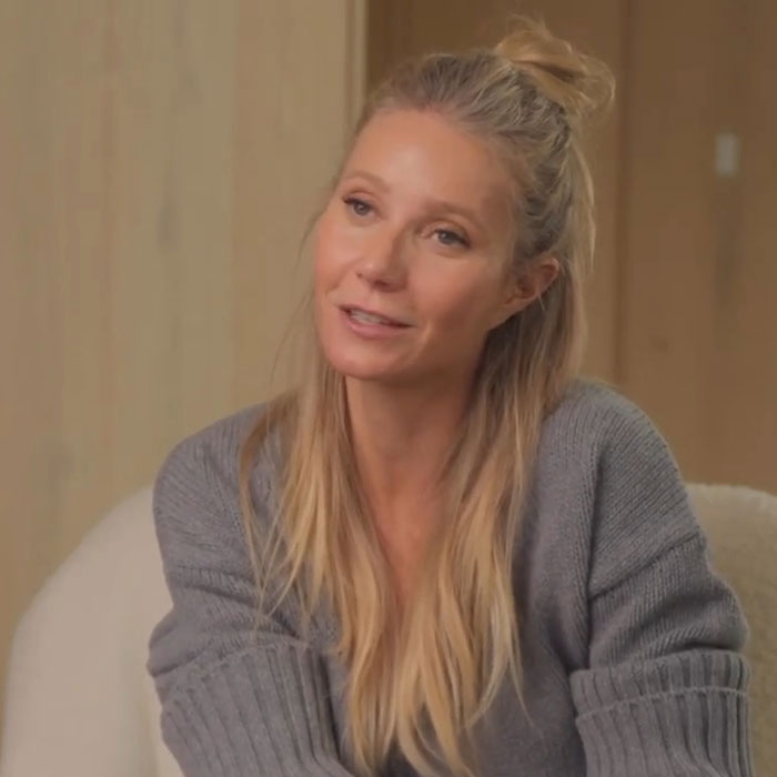 Celebrities in a relaxed setting, wearing a grey sweater, with long hair in a casual bun hairstyle.