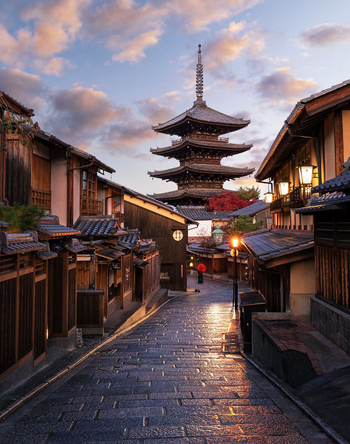 Traditional street in Japan with wooden houses and a five-story pagoda under a colorful evening sky.