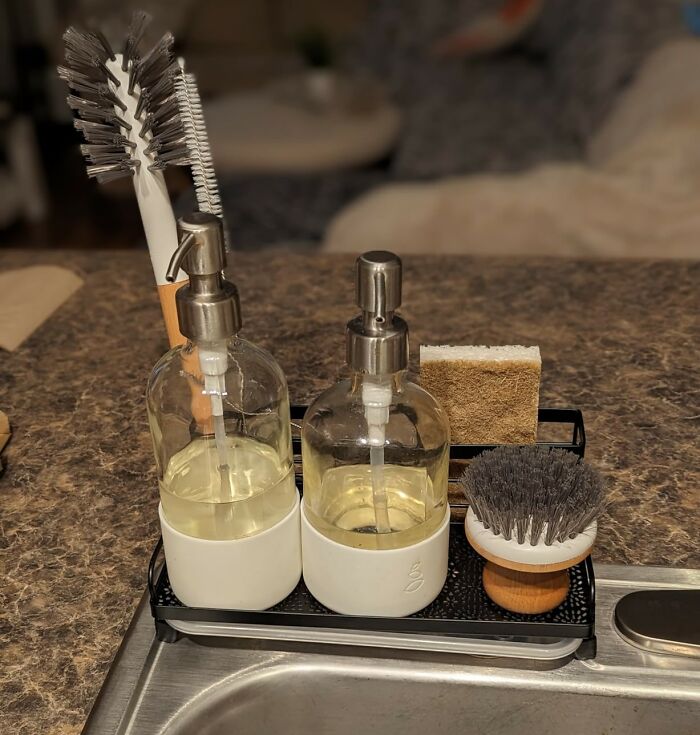 kitchen feel like new - glass soap dispensers, scrub brushes and sponge on a black tray by the sink