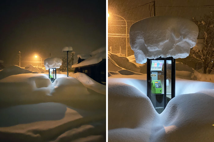 Japanese phone booth covered in heavy snow with a glowing light in a unique winter scene in Japan.