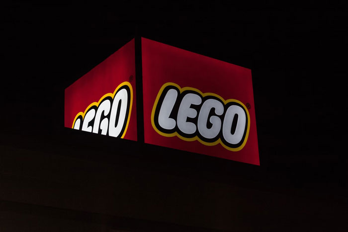 LEGO logo illuminated on a red sign against a dark background representing fun facts about toys and creativity online.