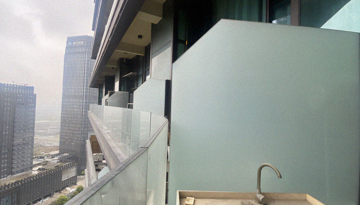 Exterior view of a Chinese dystopian apartment building with balconies overlooking an urban cityscape.