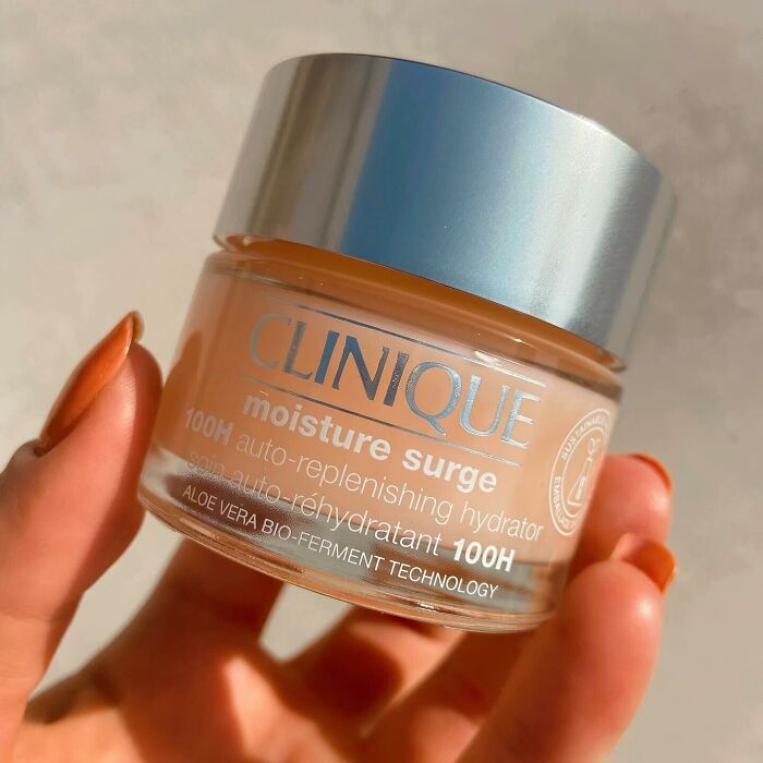 Clinique moisture surge cream held in hand, showcasing top beauty brands setting gold standard in 2024.