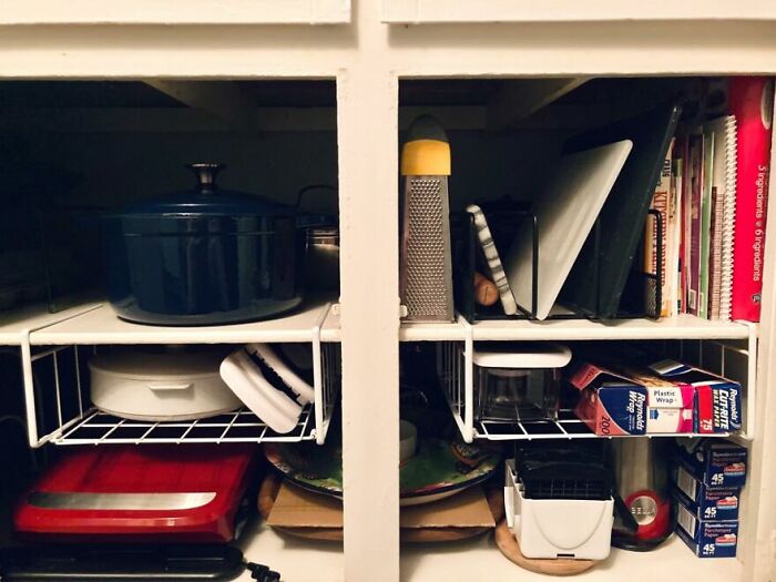 Organized kitchen cabinet with cookware, wire racks, grater, baking dishes and storage boxes, kitchen feel like new