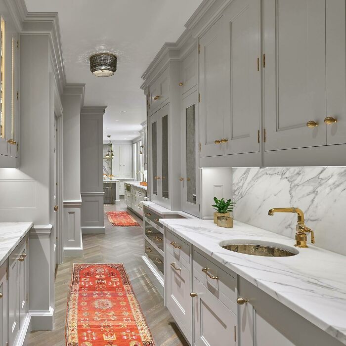 Bright galley kitchen with marble countertops, gold fixtures, and gray cabinetry showcasing galley kitchen ideas.