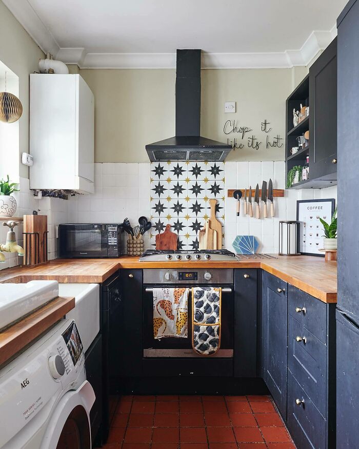 Compact galley kitchen with dark cabinets, wooden countertops, patterned backsplash, and modern appliances in a small space.
