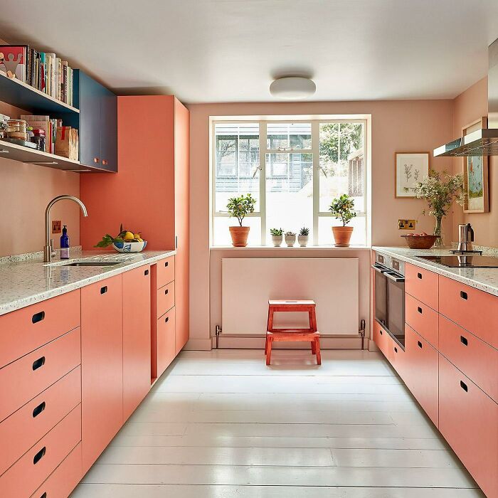 Bright galley kitchen with coral cabinets, white countertops, and natural light showcasing small space kitchen ideas.