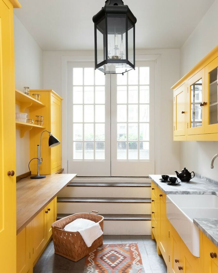 Bright galley kitchen with yellow cabinets, natural wood countertops, and a large window letting in natural light.