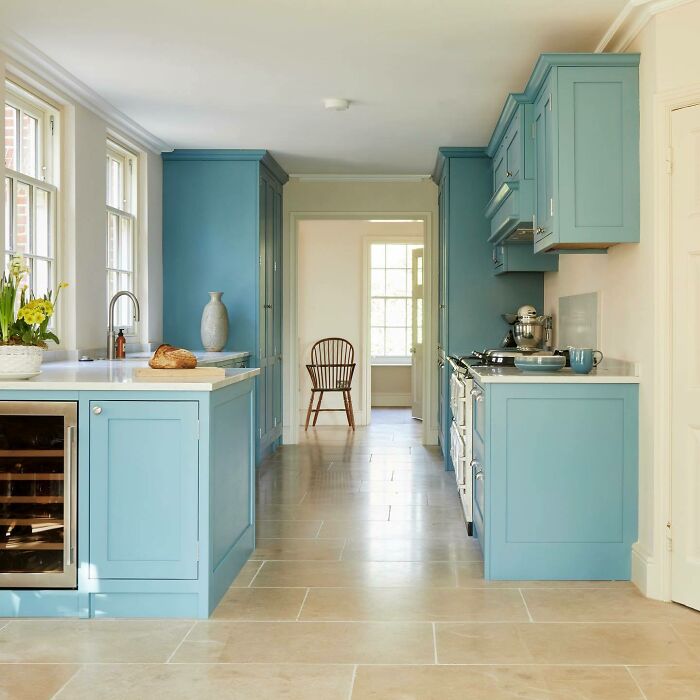 Bright galley kitchen with blue cabinetry, stone flooring, and natural light showcasing modern small space kitchen ideas.