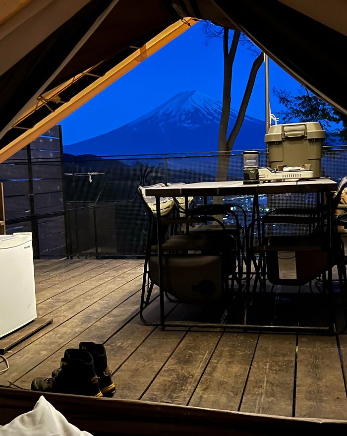 Cozy Japanese cabin deck with outdoor dining and boots, offering a stunning dusk view of Mount Fuji in Japan.
