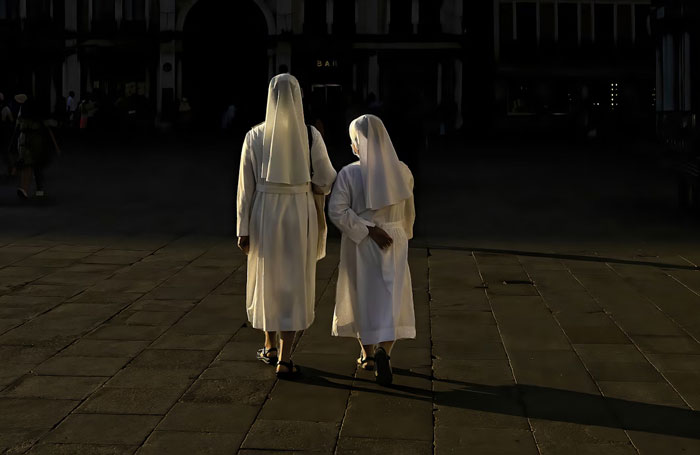 Two nuns walking on a paved street at night, illustrating 150 weird fun facts shared in an online thread.
