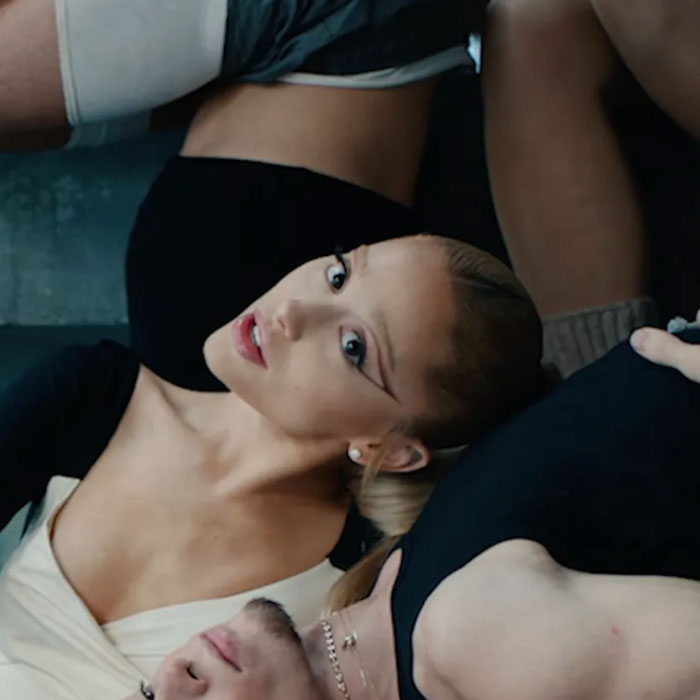 Young woman with bold eyeliner surrounded by people, illustrating famous people accused of plastic surgery.