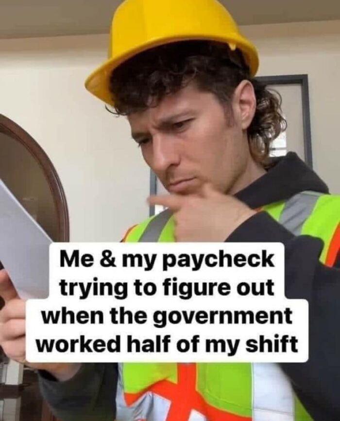 A construction worker in a hard hat and vest reads a paper, showcasing funny work meme humor.