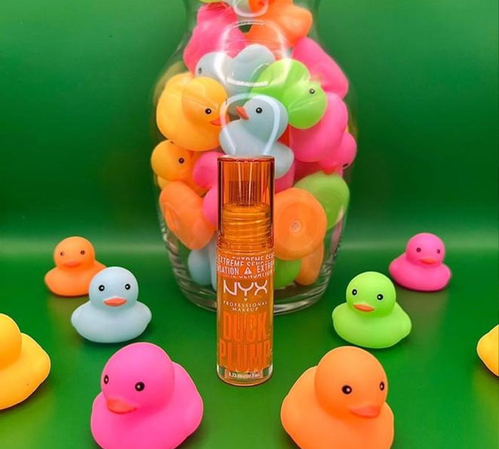 NYX Duck Plump lip product surrounded by colorful rubber ducks on a green background, beauty brands in 2024.