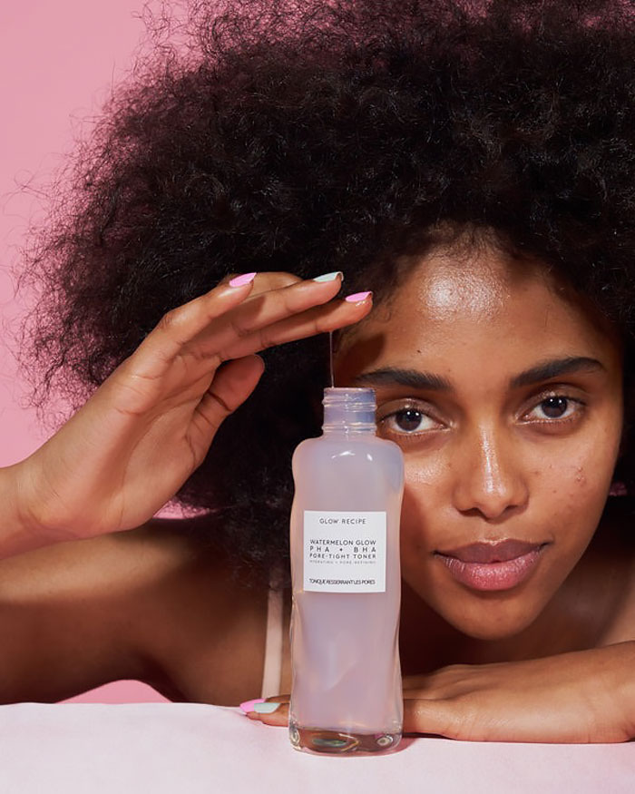 Model with natural hair holding a Glow Recipe skincare product showcasing beauty brands setting the gold standard in 2024.