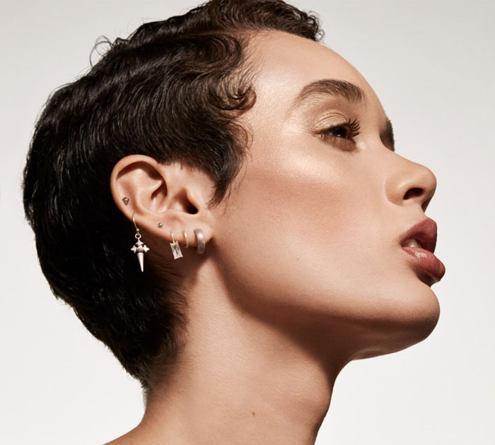 Close-up profile of a person with flawless skin and stylish earrings showcasing beauty brands setting the gold standard in 2024.