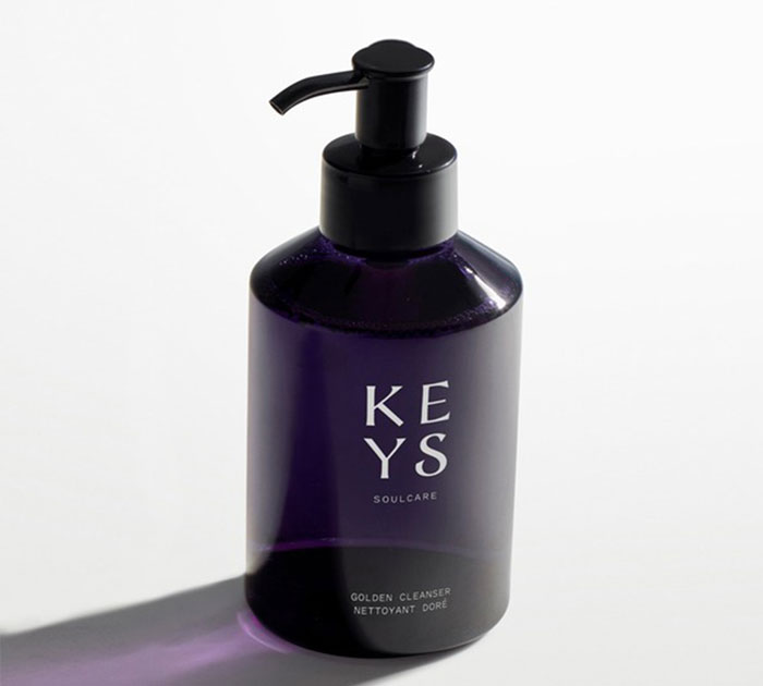 Dark purple pump bottle of beauty cleanser from a leading beauty brand setting standards in 2024 against a white background.