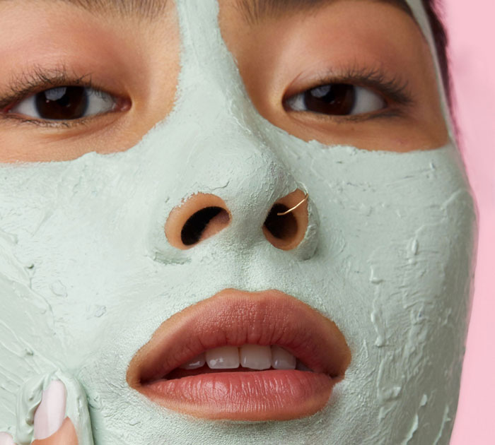 Close-up of a woman applying a beauty face mask, highlighting skincare from top beauty brands in 2024 trends.