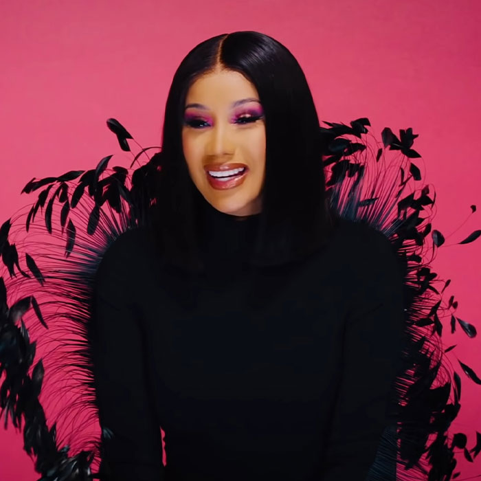 A famous woman with bold makeup and straight black hair against a pink backdrop discusses plastic surgery rumors.