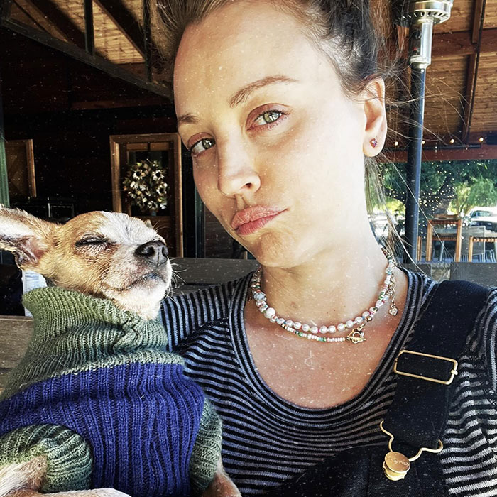 Young woman posing with small dog wearing sweater, related to famous people accused of plastic surgery rumors and responses.