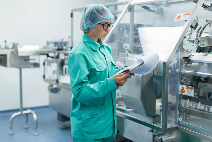 Technician in a lab coat inspecting dog food labels on a production line.