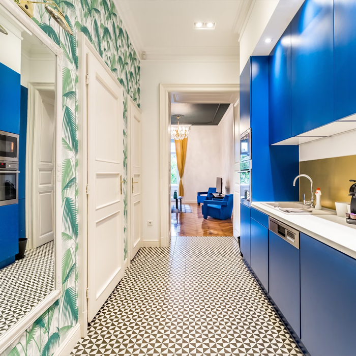 Modern galley kitchen with bold blue cabinets, geometric flooring, and patterned wallpaper showcasing small space kitchen ideas.