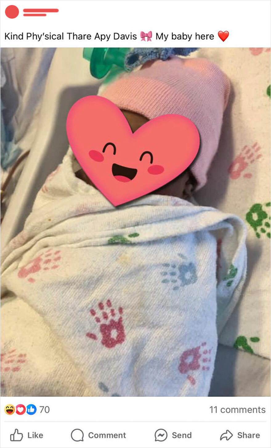 Baby with a hilariously unfortunate name wrapped in a printed blanket, heart emoji over face.