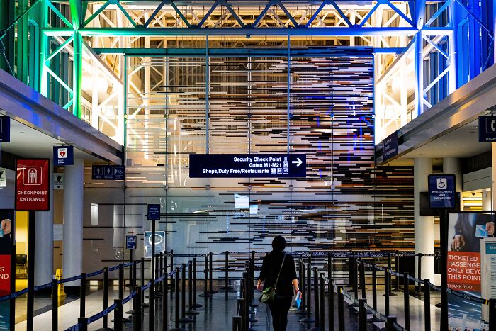 Traveler walking through airport security checkpoint with signs and a modern architectural interior, illustrating trivia-worthy facts.