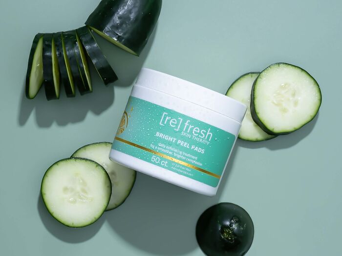 Skincare product from beauty brands featuring bright peel pads surrounded by fresh cucumber slices on a green background.