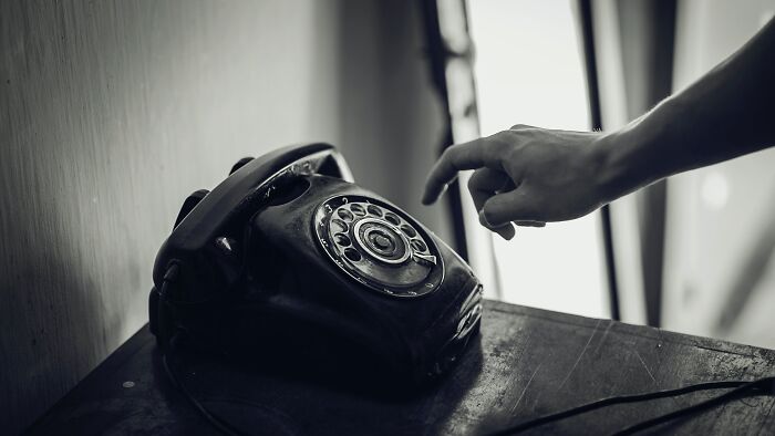 Hand dialing an old rotary phone, illustrating trivia-worthy facts about the past and vintage communication technology.