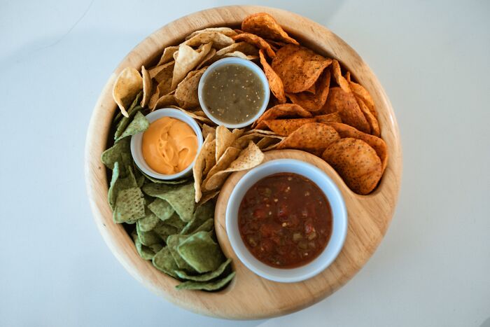 Assorted chips and dips arranged on a wooden platter illustrating advice people thought was a joke until trying it