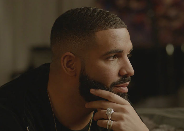 Man with a beard and short hair wearing rings, thoughtfully looking to the side, representing famous people declining major awards.