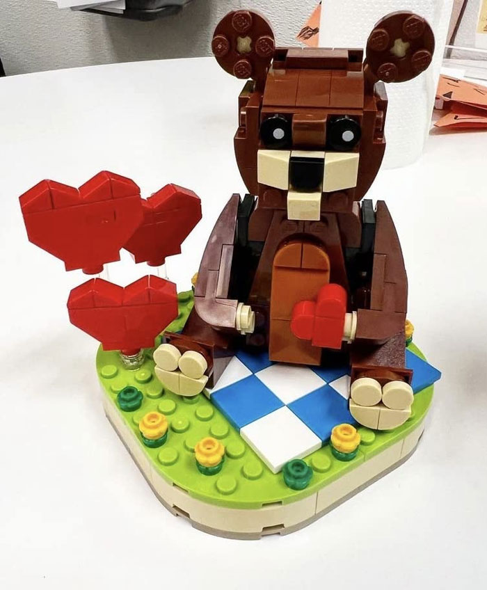 LEGO bear holding hearts on a picnic blanket, a fun Valentine's Day gift for kids.