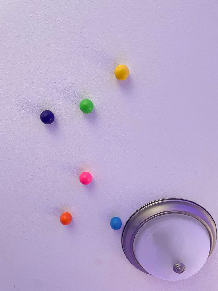 Colorful balls stuck to the ceiling near a light fixture, perfect for Valentine's Day gifts kids love.