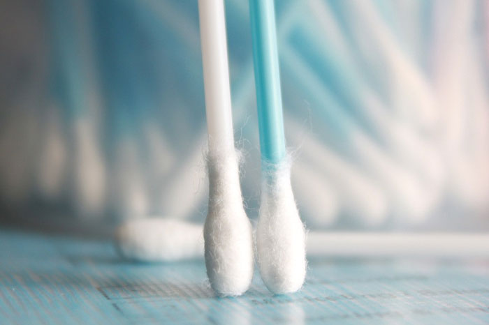 Close-up of cotton swabs related to cats' earwax attraction, against a blurred background.