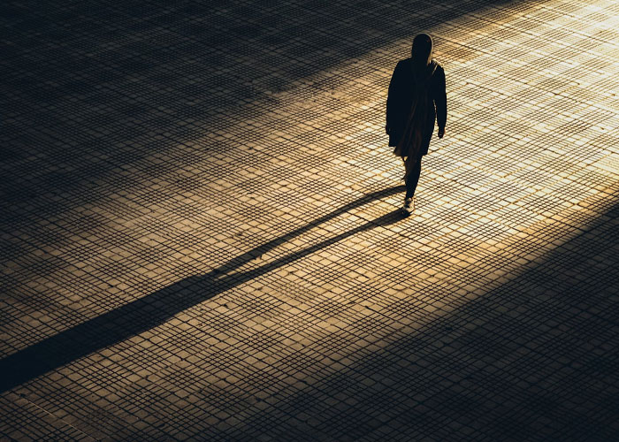 Person walking alone casting a long shadow on tiled ground, symbolizing childfree people over 40 reflecting on life choices.