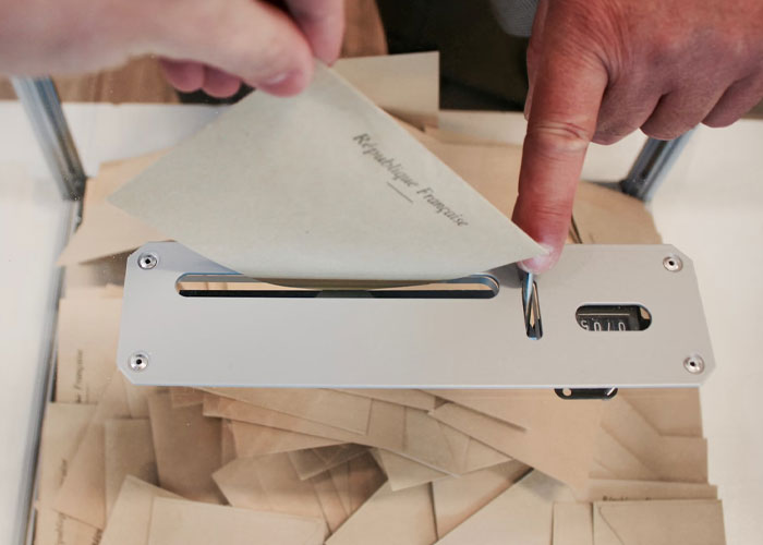 A person inserting a paper envelope into a silver ballot box, illustrating people confess things they didn’t know late in life.