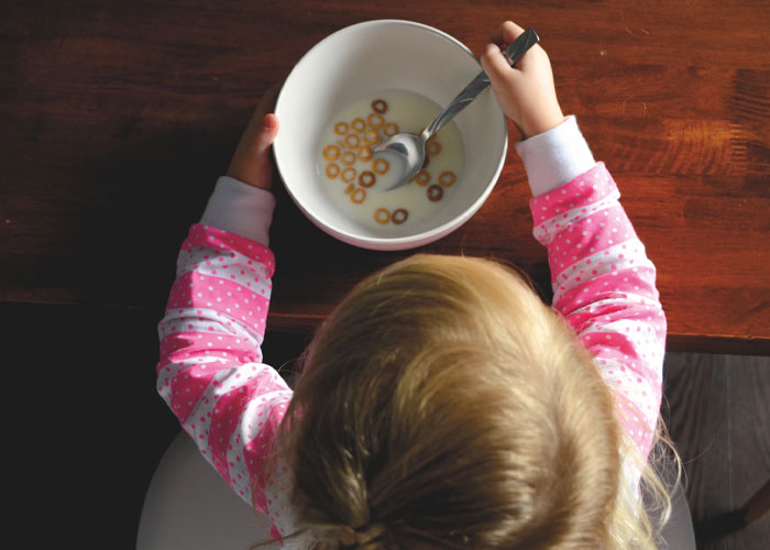 Childfree person over 40 having breakfast, reflecting on life choices in a quiet, wooden dining room setting.