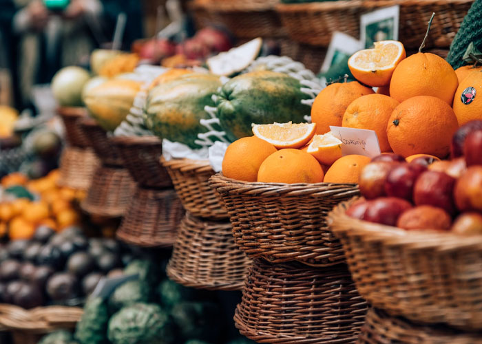 Basket baskets filled with fresh oranges and other fruits at a market, showing vibrant colors and natural textures.